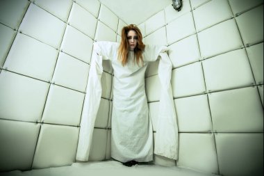 Tımarhane izole bir odada deli gömleği giymiş çılgın bir kız portresi.