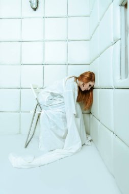 Tımarhane izole bir odada deli gömleği giymiş çılgın bir kız portresi.