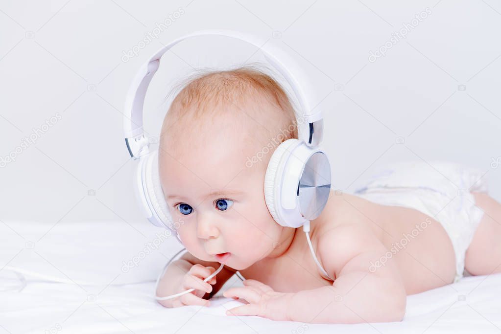 Cute three-month-old baby listening to music in headphones.