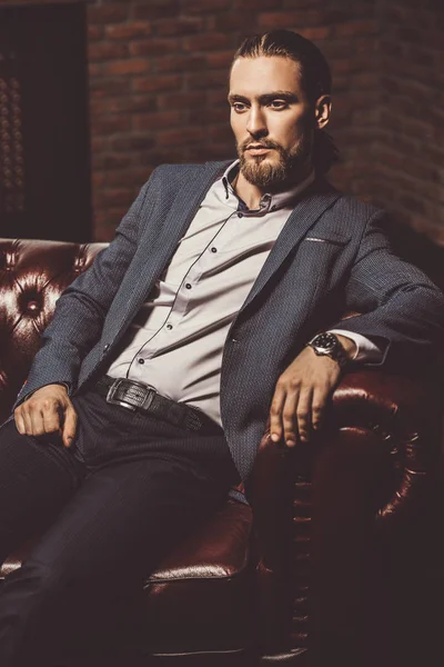 Modern bir iç bir deri kanepede oturan genç adam heybetli. Erkek güzelliği, moda.