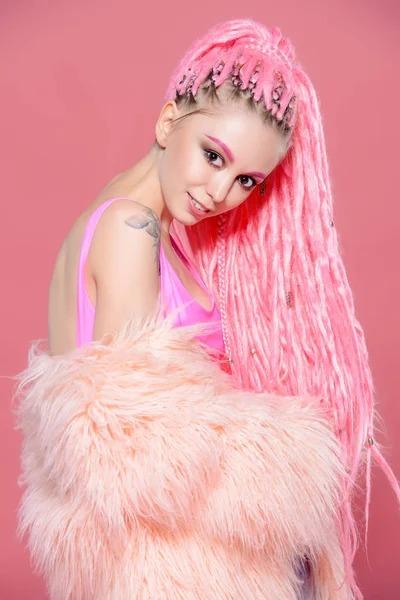 Şık kız pembe dreadlocks pembe bir arka plan üzerinde parlak giysiler içinde poz ile. Güzellik, moda.