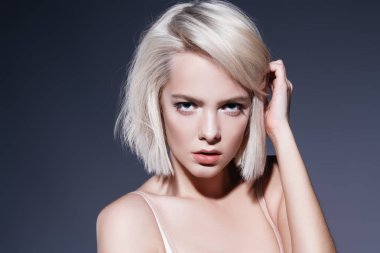 Koyu arka plan üzerinde çıplak makyaj güzel bir sarışın kadınla yakın çekim portre. Güzellik, moda kavramı. Kalıcı makyaj ve kozmetik. Kısa saçlar için saç kesimi.