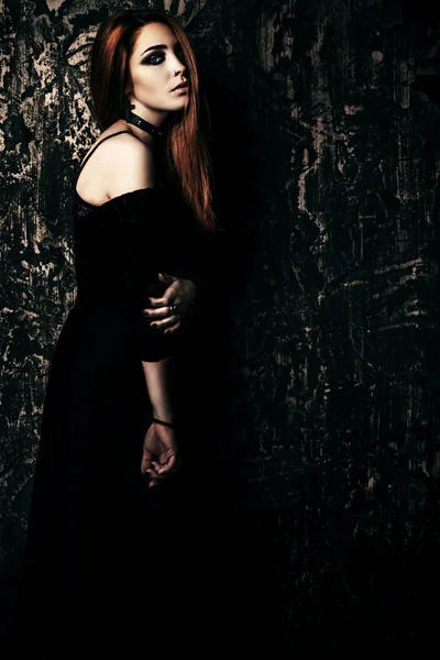 Magnificent woman in black gothic dress over grunge background. Fashion. Gothic style.