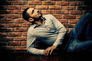 Bir tuğla duvar tarafından poz yakışıklı bir brunet adam portresi. Erkek güzelliği, moda. Erkek Berber Dükkanı, saç modeli.