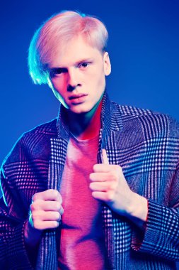 Stüdyoda gri arka plan üzerinde poz yakışıklı bir genç adam sarı saçlı bir ekose ceket giyen portresi. Erkek güzellik ve sağlık.