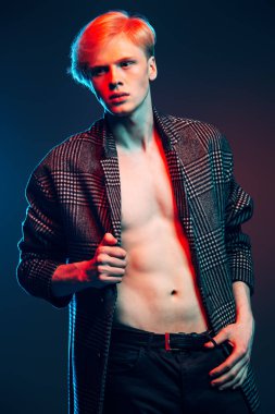 Vogue yakışıklı bir erkek model gri arka plan üzerinde kareli ceket daimi bir kadeh. Erkek güzelliği, moda. 