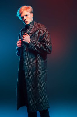 Stüdyoda gri arka plan üzerinde poz yakışıklı bir genç adam sarı saçlı bir ekose ceket giyen portresi. Erkek güzellik ve sağlık.