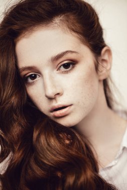 Yakın çekim beyaz arka plan üzerinde uzun kıvırcık kırmızı saçlı bir on beş yaşındaki kız portresi. Güzellik, moda.