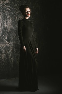 Siyah uygun uzun elbise giyen zarif genç kadın. Güzellik, moda kavramı. Stüdyo vurdu.