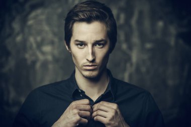 Yakın çekim mavi gömlekli koyu arka plan üzerinde koyu renk saçlı genç bir adam portresi. Erkek güzellik ve sağlık.