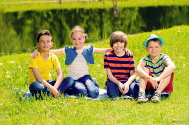 Neşeli çocuklar parkta dinlenme grubudur. Açık hava etkinliği. Yaz tatili.