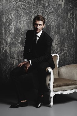 Grunge arka plan üzerinde şık bir takım elbise içinde yakışıklı bir adam portresi. Stüdyo vurdu.