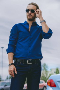 Kot pantolon giysili yakışıklı genç bir şehir sokak üzerinde duruyor. Erkek moda.