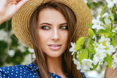 Bir çiçek bahçesinde poz hasır şapkalı güzel kız.