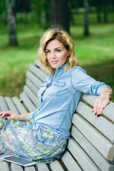 Mutlu orta yaşlı kadın rahatlatıcı bir yaz gününde parkta bir bankta. Yaz ve tasasız tatiller ruh hali. Güzellik, kozmetik.