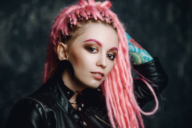 Kadın modeli pembe dreadlocks karanlık bir arka plan üzerinde poz ile çarpıcı. Son moda saç modelleri. Güzellik, moda. 