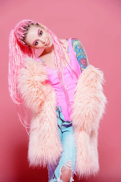 Şık kız pembe dreadlocks pembe bir arka plan üzerinde parlak giysiler içinde poz ile. Güzellik, moda.