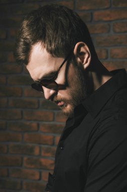 Siyah gömlek ve güneş gözlüğü takan yakışıklı sakallı adam. Erkek moda.