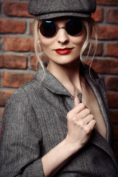 Gri ceket, şapka ve gözlük cinsel bir genç kadının portresi. Güzel akıllı kız. Güzellik, moda.