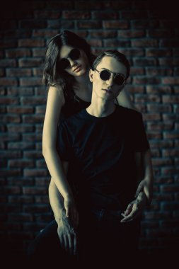 Güzel genç bir çift bir tuğla duvara yakın poz aşık. Güzellik, moda.