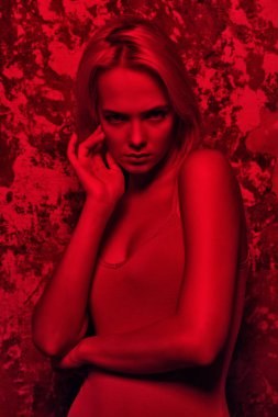 Ten rengi elbise kırmızı ışık Studio poz çekici genç kadın. Güzellik, moda.