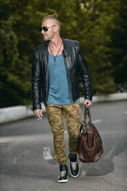 Yakışıklı acımasız adam yolda yürürken deri ceketli. Motorcu adam gezi gidecek. Bağımsızlık ruhu.
