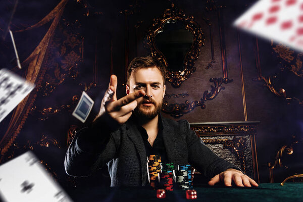 A wealthy mature man playing poker in a casino. Gambling, playing cards and roulette.