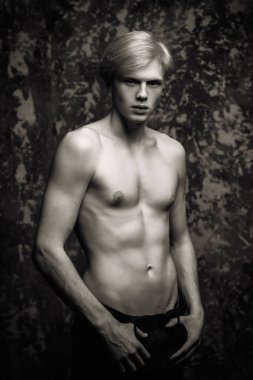 Portre gömleksiz bir gencin stüdyoda grunge arka plan üzerinde poz sarışın saçlı. Erkek güzellik ve sağlık.