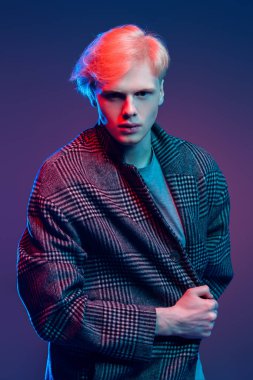 Stüdyoda gri arka plan üzerinde poz yakışıklı bir genç adam sarı saçlı bir ekose ceket giyen portresi. Erkek güzellik ve sağlık.