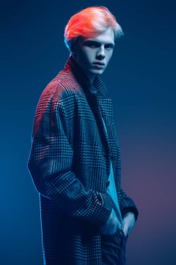 Stüdyoda gri arka plan üzerinde poz yakışıklı bir genç adam sarı saçlı bir ekose ceket giyen portresi. Erkek güzellik ve sağlık.