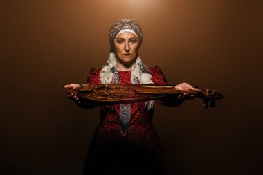 Ulusal kostüm yaşlı yerli kadın eski keman çalıyor.