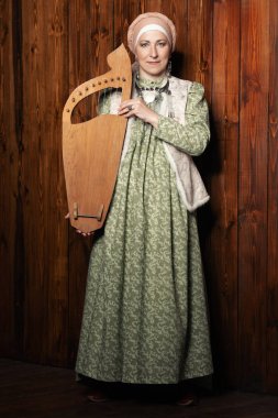 Yaşlı yerli kadın Ulusal kostüm arp çalıyor. Tam uzunlukta portre.