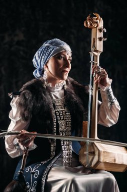 Ulusal kostüm yaşlı yerli kadın eski keman çalıyor.