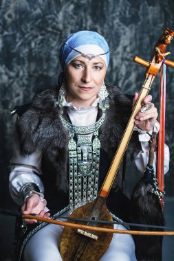 Ulusal kostüm yaşlı yerli kadın eski keman çalıyor.