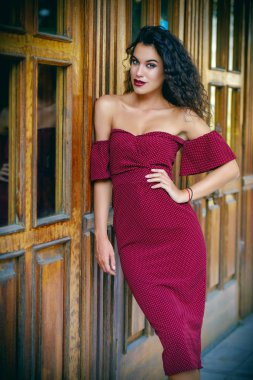 Esmer kadın büyüleyici bir şehir sokak üzerinde zarif bordo elbise giymiş. Güzellik, moda kavramı. Kozmetik ve makyaj.