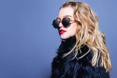 Siyah güneş gözlüğü ve kürk giyen çekici genç kadın. Stüdyo vurdu. Güzellik, moda kavramı.