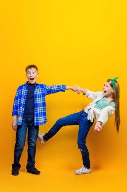 Parlak sarı bir arka plan üzerinde iki duygusal çocuk portresi. Çocuk moda.