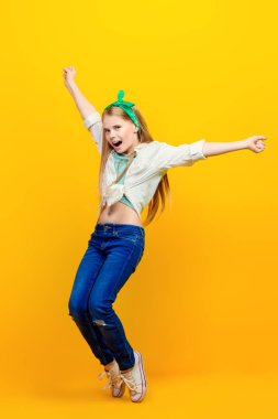 Çocuk moda. Stüdyoda sarı arka plan üzerinde atlama sarı elbiseli güzel küçük kız.