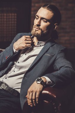 Modern bir iç bir deri kanepede oturan genç adam heybetli. Erkek güzelliği, moda.