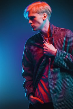 Stüdyoda gri arka plan üzerinde poz yakışıklı bir genç adam sarı saçlı bir ekose ceket giyen portresi. Erkek güzellik ve sağlık.