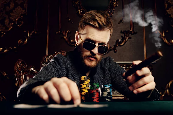 A wealthy mature man playing poker in a casino. Gambling, playing cards and roulette.