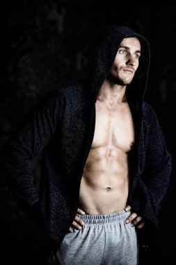 Hoodie yakışıklı atletik adam bir grunge duvar tarafından duruyor. Spor ve vücut geliştirme kavramı. Sağlıklı yaşam tarzı.