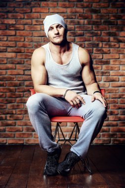 Kaslı atletik erkek bir tuğla duvar tarafından duruyor. Spor yaşam tarzı. Vücut geliştirme. 