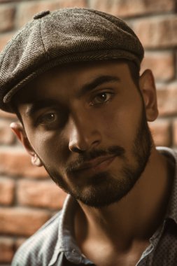 Tuğla duvar arka plan üzerinde bir kap içinde yakışıklı bir brunet adam portresi. Erkek güzelliği, moda. Erkek berber.