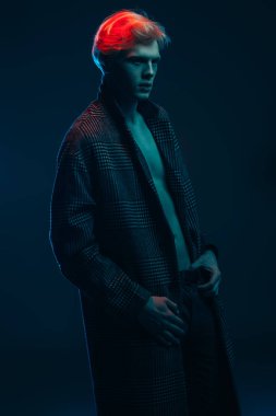 Vogue yakışıklı bir erkek model gri arka plan üzerinde kareli ceket daimi bir kadeh. Erkek güzelliği, moda. 