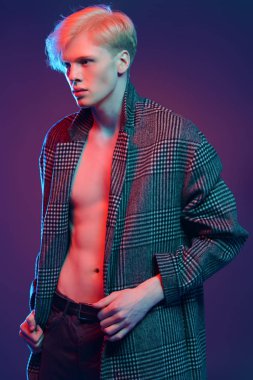 Vogue yakışıklı bir erkek model gri arka plan üzerinde kareli ceket daimi bir kadeh. Erkek güzelliği, moda. 