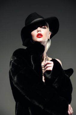Gorgeous blonde woman posing in luxurious fur coat and a hat. Fashion, beauty. Studio shot. clipart