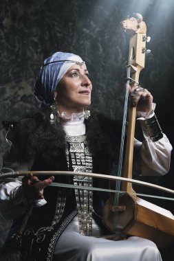 Ulusal kostüm yaşlı yerli kadın eski keman çalıyor.
