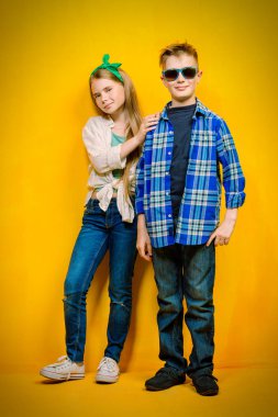 Parlak sarı bir arka plan üzerinde iki duygusal çocuk portresi. Çocuk moda.