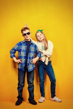 Parlak sarı bir arka plan üzerinde iki duygusal çocuk portresi. Çocuk moda.